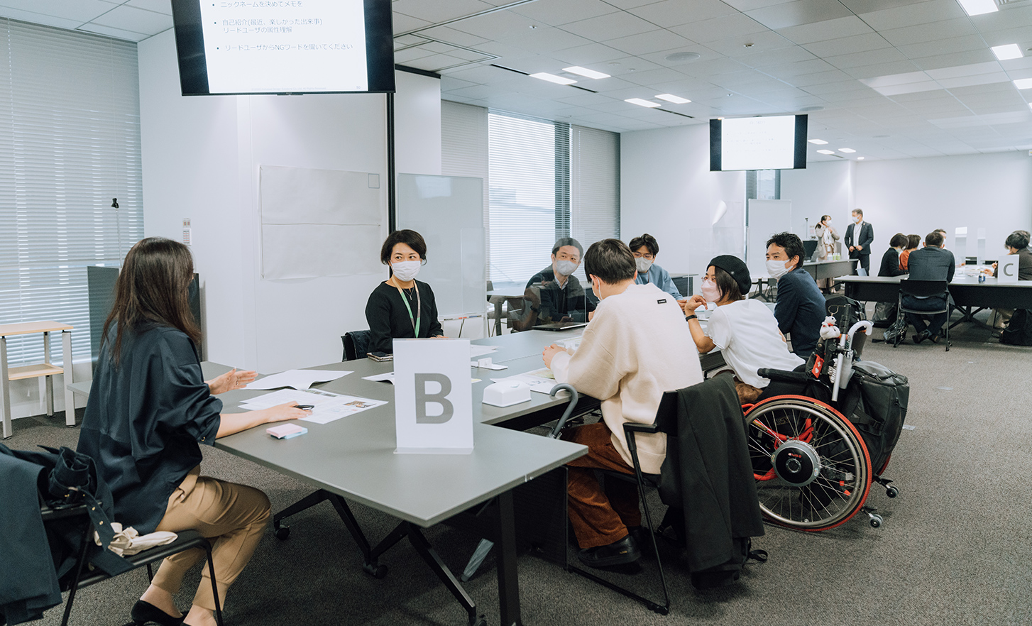 Employees and wheelchair user are sitting around a table and discussing