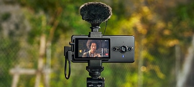 Vlog Monitor attached to smartphone fitted with Bluetooth shooting grip and external microphone