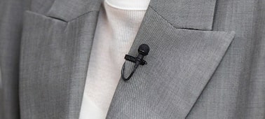 Usage image of a woman with an ECM-L1 microphone with metal windscreen on her suit lapel