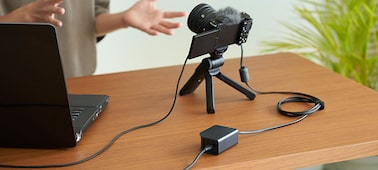 Usage image showing a user streaming with a ZV-E10 II camera to which power is supplied from the DC-C1.