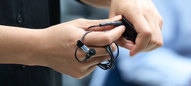 Usage image of a woman attaching the locking ring of the ECM-L1 microphone to a wireless microphone transmitter