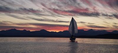 Image showing sailboat on lake against sunset with patterned sky and darker hills