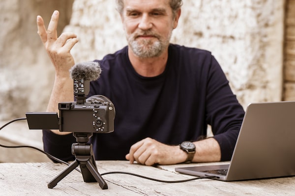 Usage image showing a user live streaming with the camera standing on the extension grip stand